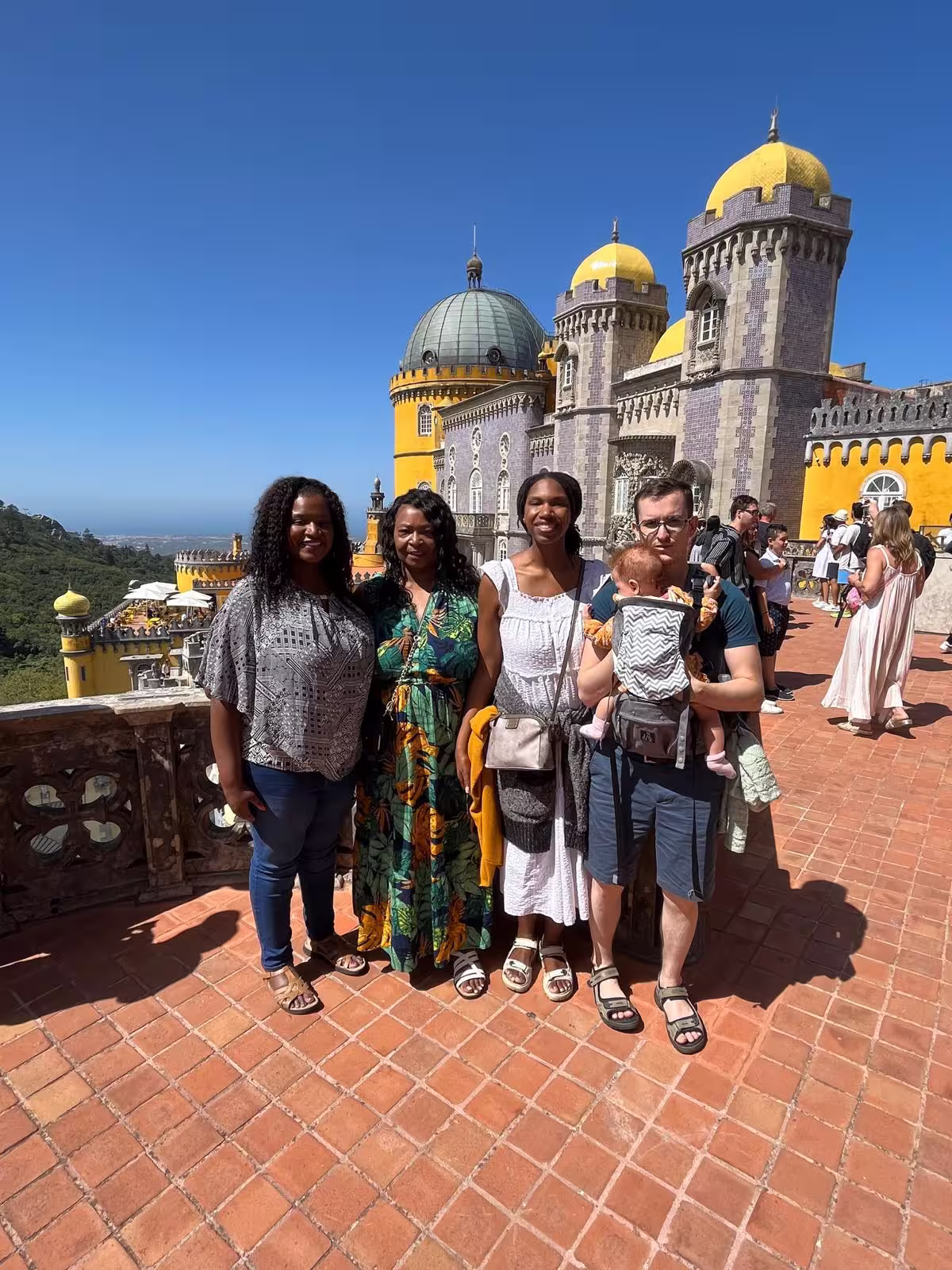 Visitors enjoy a sunny day at Sintra's vibrant Pena Palace, showcasing its iconic architecture and stunning views.