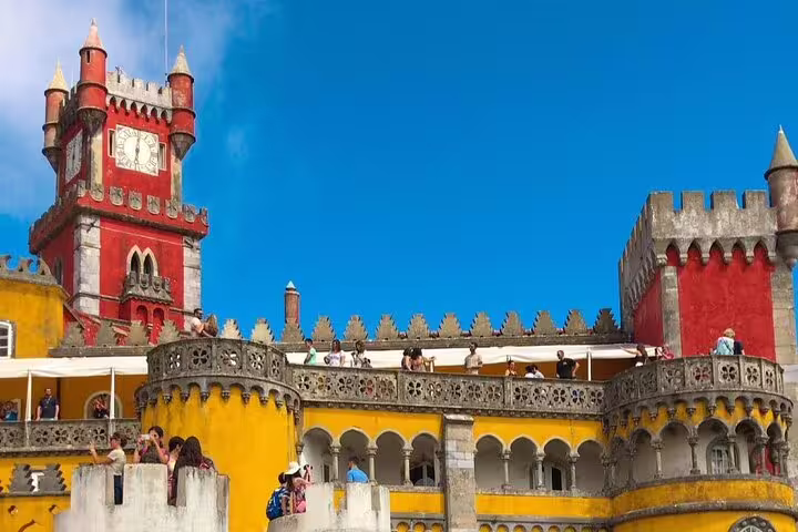 Vibrant Pena Palace in Sintra under blue skies, showcasing its colorful architecture on a guided tour of the Sintra Mountains.