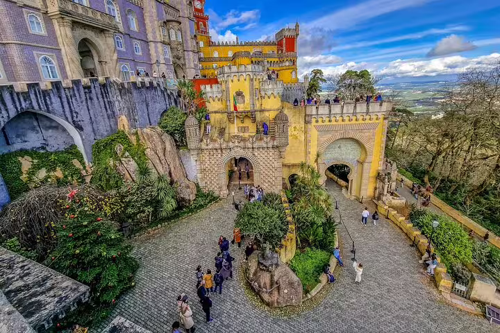 Colorful Pena Palace in Sintra, Portugal, surrounded by lush greenery and tourists, featured on Sintra, Roca, Cascais tour.