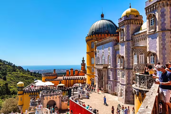Vibrant view of Pena Palace in Sintra with tourists exploring the colorful architecture and scenic landscapes on a sunny day.