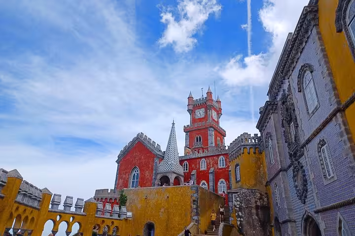 Colorful Pena Palace in Sintra seen on tuk tuk tour, red towers and yellow walls under blue sky