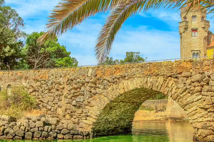 Scenic stone bridge near Pena Palace on a sunny day, surrounded by lush greenery, featured in Sintra day tour.