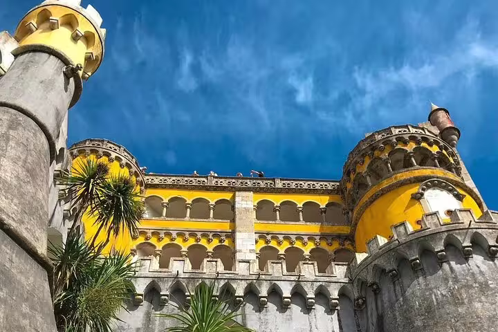 Vibrant yellow turrets of Pena Palace under a clear blue sky, featured in the Sintra and Cascais full-day tour.