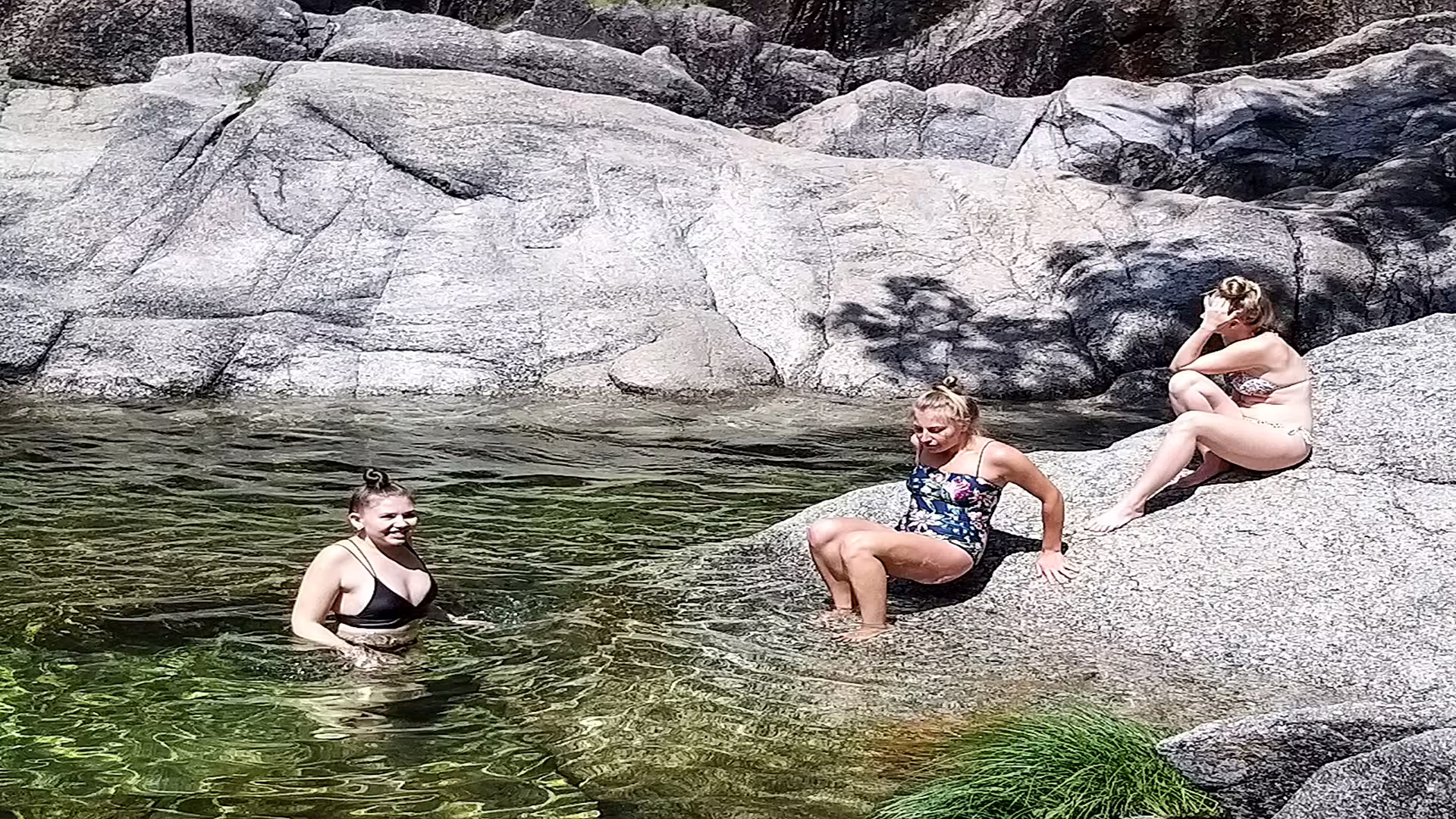 Visitors enjoy a refreshing swim in a natural pool surrounded by rocky landscapes at Peneda-Gerês National Park.