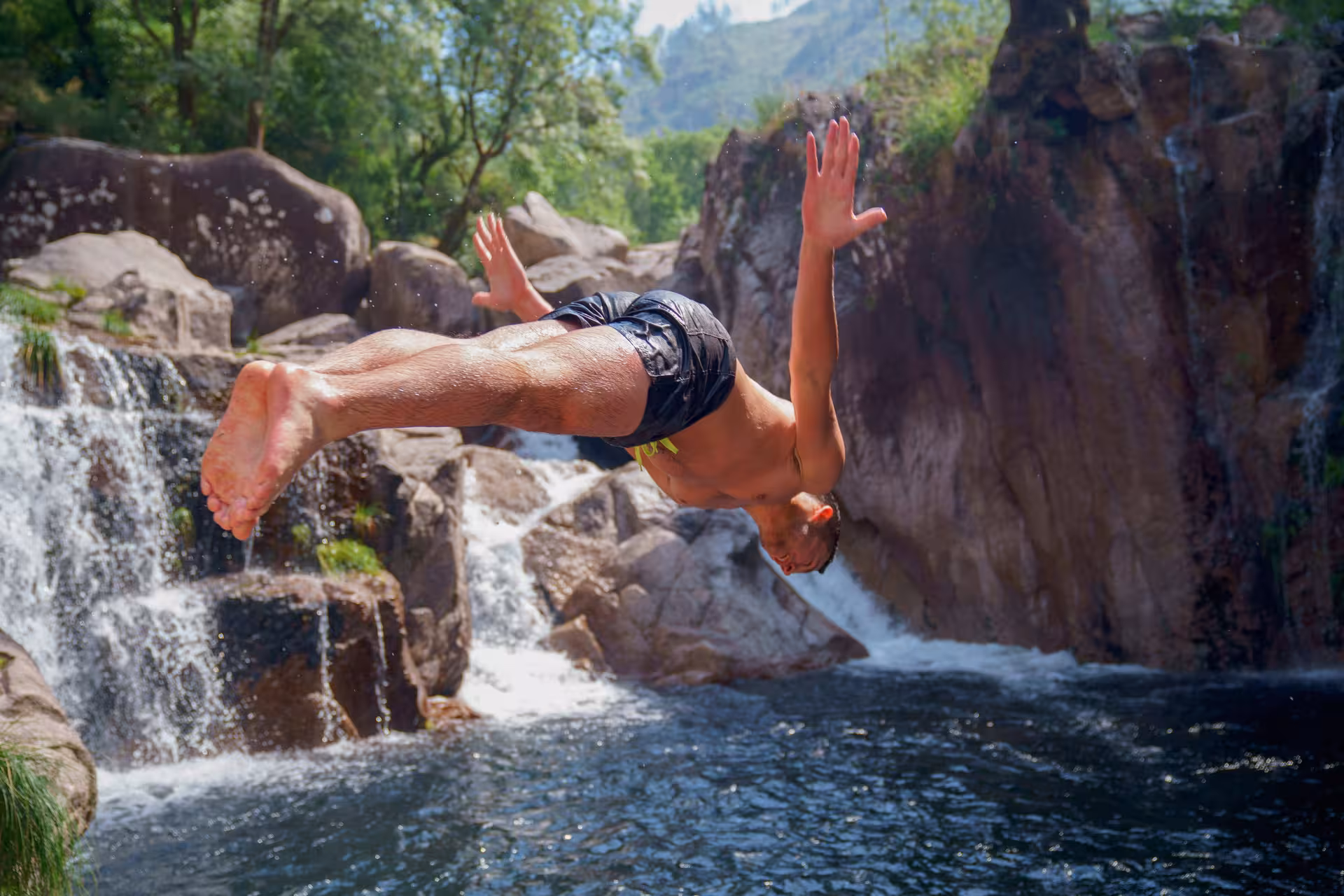 Adventurer diving into natural pool at Peneda-Gerês National Park waterfall, perfect for an exhilarating tour experience.
