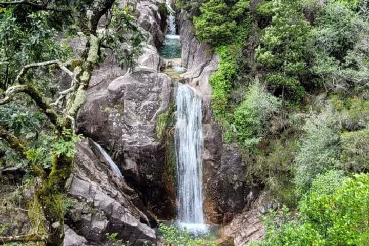 Stunning waterfall surrounded by lush greenery in Peneda-Gerês National Park, perfect for nature tours and hikes.