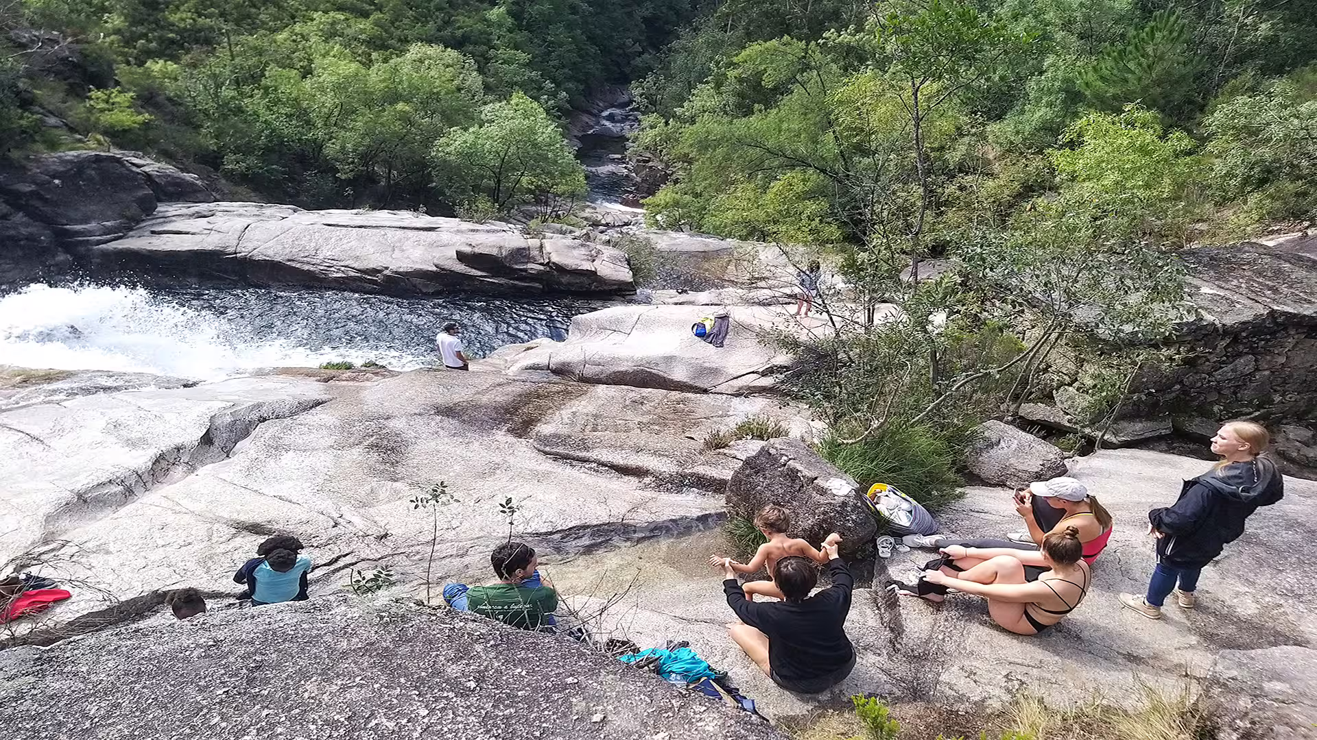 Visitors enjoy a scenic view of a waterfall and lush greenery during a private tour at Peneda-Gerês National Park.
