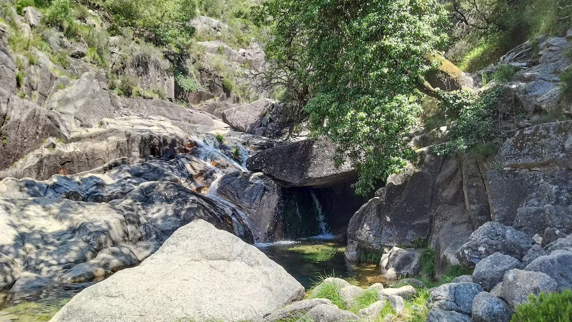 Scenic waterfall cascading over rocky terrain surrounded by lush greenery in Peneda-Gerês National Park, ideal for nature tours.
