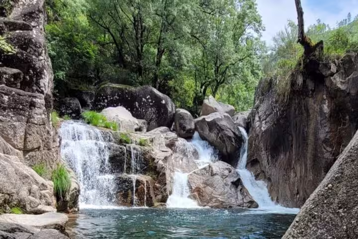 Scenic waterfall cascading over rocks amid lush greenery in Peneda Geres National Park on a private tour from Porto.