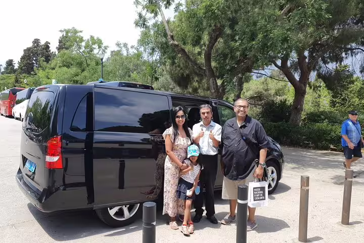 Tour group stands by a sleek black van ready to explore the Penedés wine region on a guided cellar tour.