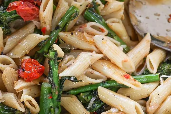 Delicious penne pasta with roasted tomatoes and broccolini, ideal for savoring on a culinary exploration tour.