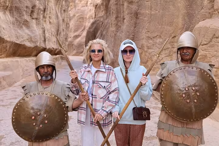 Tourists holding spears with Bedouin guards in Petra canyon, Sharm El Sheikh to Petra ferry excursion