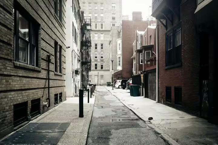 Narrow historic brick alley in Philadelphia with fire escapes and wet pavement on a cloudy day