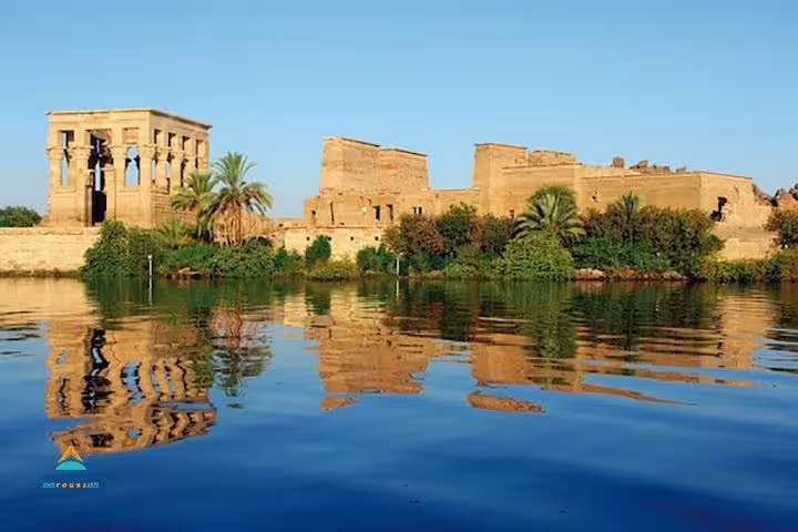 Aswan Philae Temple on the Nile with palm trees and reflections, scenic stop on Luxor to Aswan tour