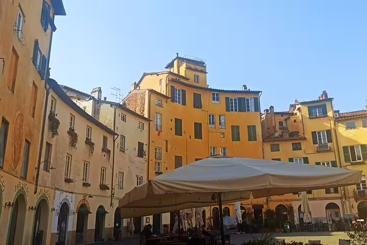Colorful medieval houses and café terrace in Piazza dell’Anfiteatro, Lucca on private Pisa and Lucca excursion