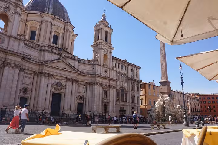 View of Piazza Navona in Rome from a cafe, showcasing historical architecture and vibrant city life, perfect for culinary tours.