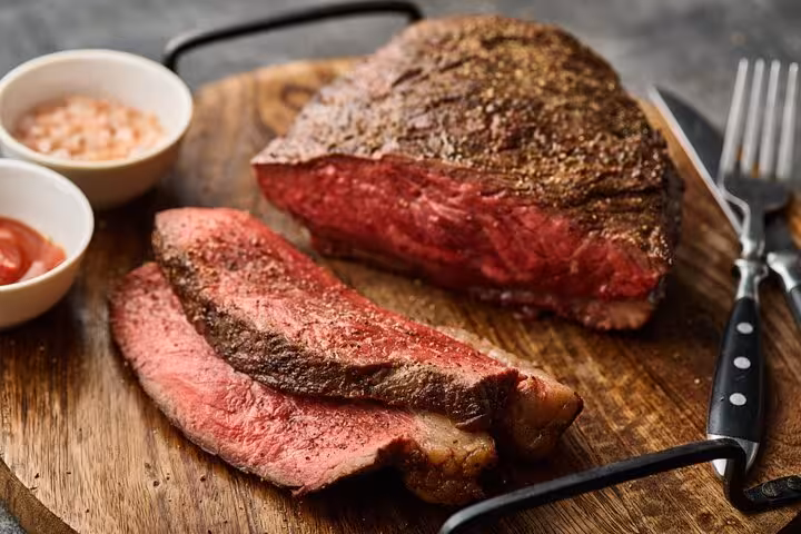Sliced picanha steak on a wooden board, representing popular Brazilian barbecue and meat dish.