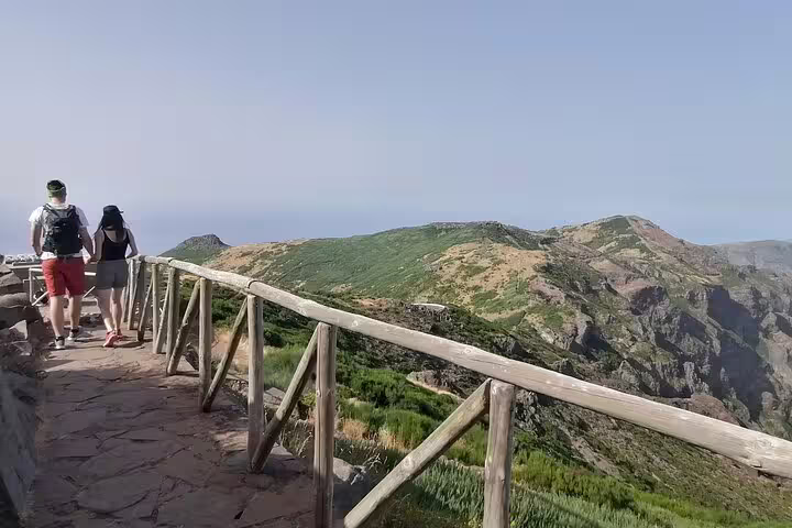 Hikers enjoy the breathtaking vistas along the Pico do Arieiro trail, surrounded by lush greenery and peaks.