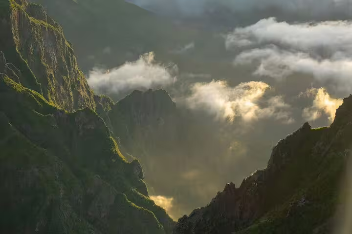 Sunlit clouds drift over dramatic mountain peaks in Pico do Arieiro, offering breathtaking views for hikers.