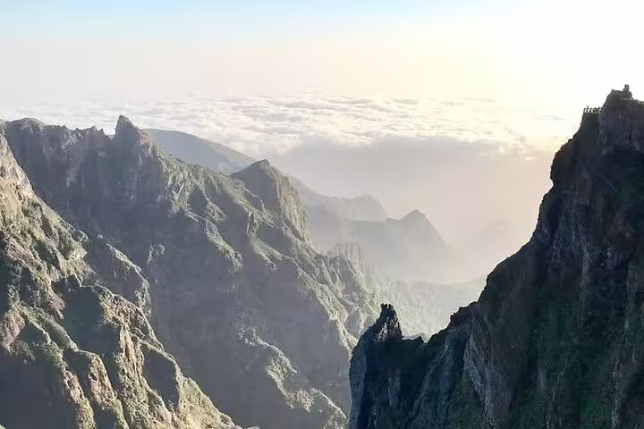 Majestic mountain landscape with jagged peaks and a sea of clouds at sunrise from Pico do Arieiro in Madeira.