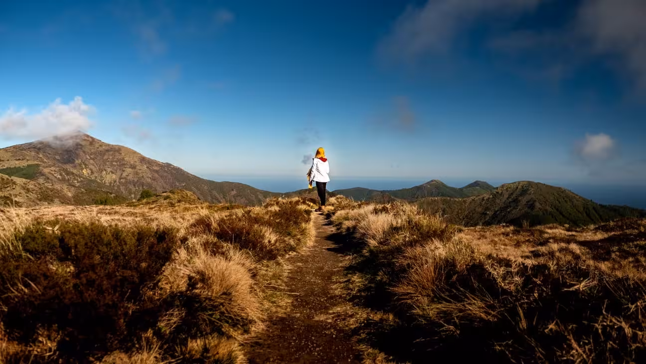 Hiker on the Pico da Vara trail in São Miguel, Azores, with volcanic ridges and ocean views on a full-day hike