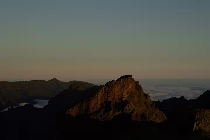Golden glow on Pico do Arieiro's peaks at dawn, offering a serene and picturesque start to your hiking journey.