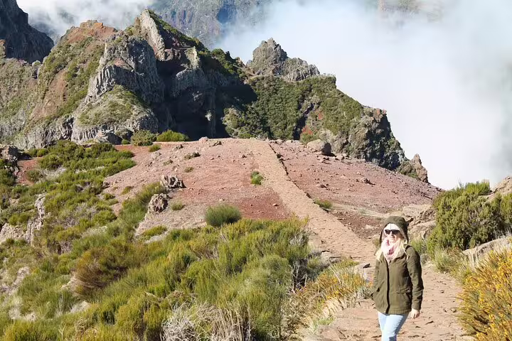 Hiker walks along rugged path with stunning mountain and cloud views on Pico do Arieiro self-guided sunrise hike.