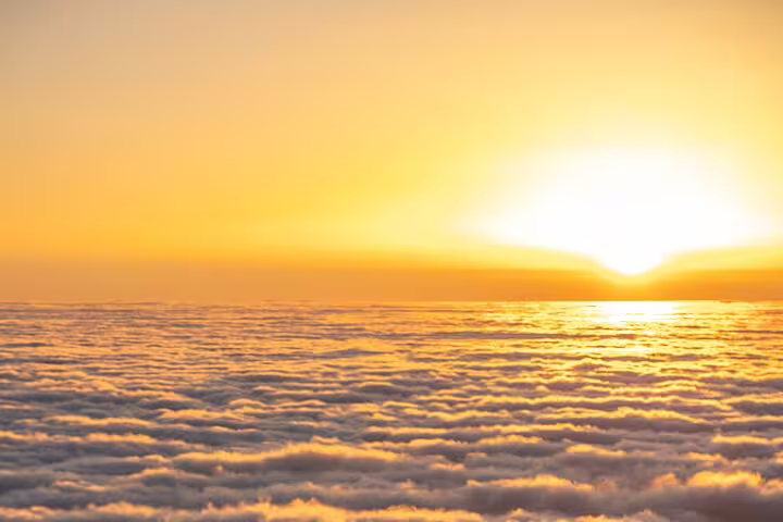 Golden sunrise over a sea of clouds at Pico do Arieiro, offering a stunning view for early morning hikers.