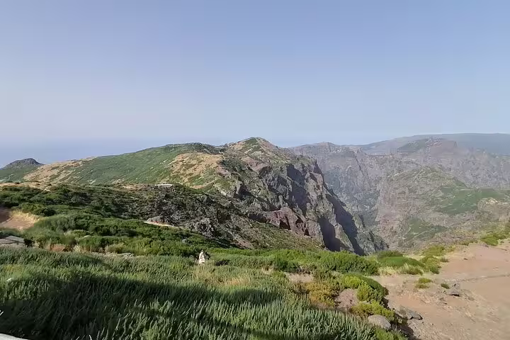 Scenic panorama of Pico Ruivo, showcasing lush greenery and dramatic cliffs under a bright, sunny sky.