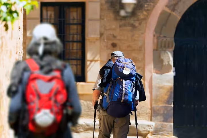 Pilgrims with backpacks walking through historic Santiago de Compostela on a private 2-hour guided city tour.