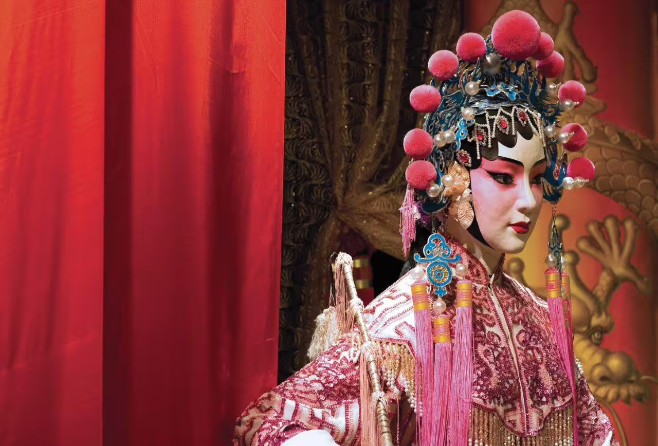 Performer in elaborate traditional costume and makeup in a vibrant Pingyao opera house.