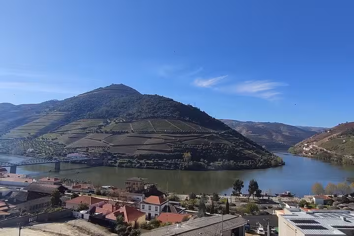 Panoramic view of Pinhão and the Douro River with terraced vineyards and hills under clear blue sky