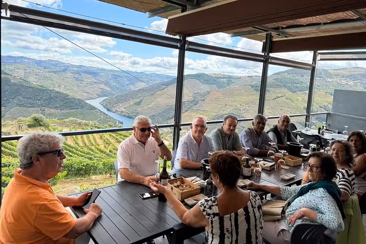 Group lunch with Douro River and vineyard views on a terrace in Pinhão, featuring local wine tasting