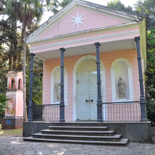 Charming pink chapel surrounded by lush greenery in Tijuca Forest, a highlight of the private tour.