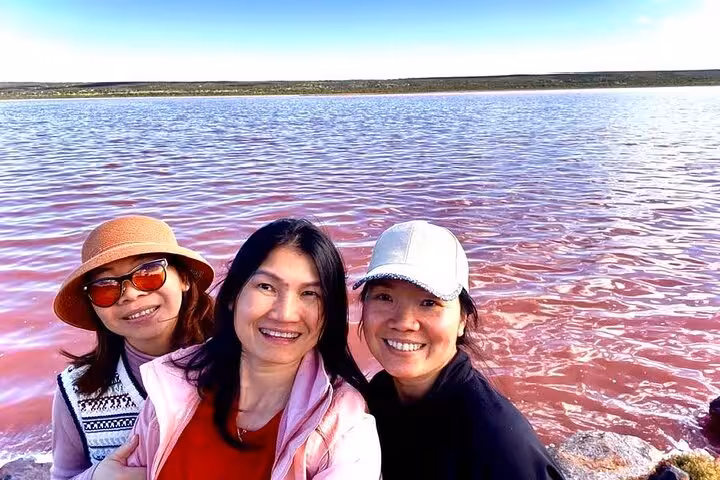 Three friends smiling by the vibrant Pink Lake, enjoying the scenic 2-day tour at Natures Window and Pinnacles.