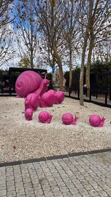 Vibrant pink snail sculptures displayed in a modern outdoor art exhibit, perfect for creative sculpture tours.