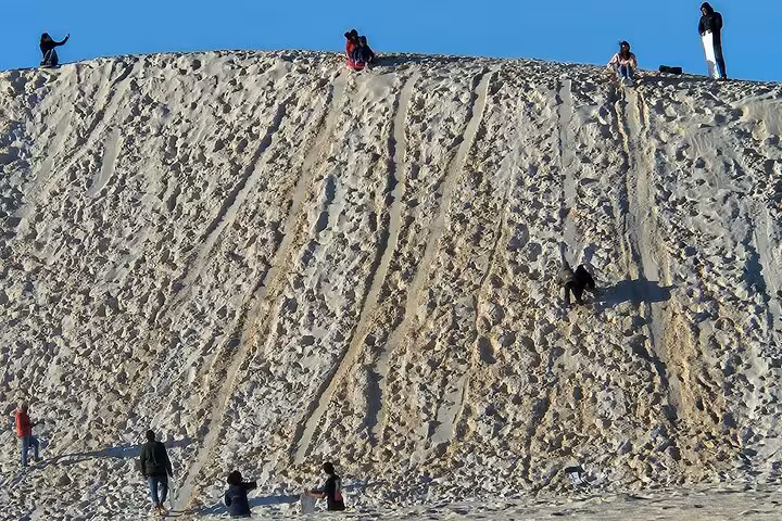 Adventure seekers climbing a steep sand dune during the Pinnacle Day Adventure Tour, perfect for thrill-lovers.