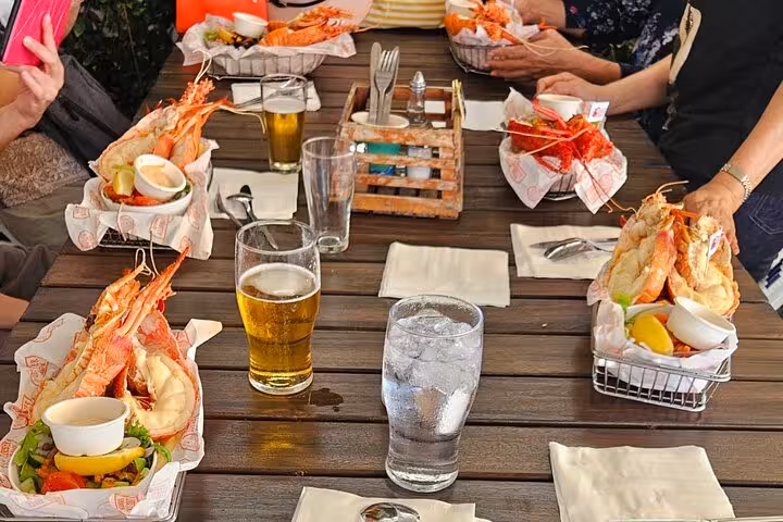 Group enjoying seafood platters and drinks at an outdoor table during a Pinnacle Day Adventure Tour.