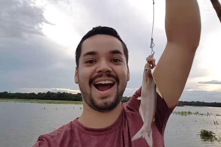 Traveler holding a freshly caught piranha on the Solimões River, Amazon fishing experience near Manaus Brazil