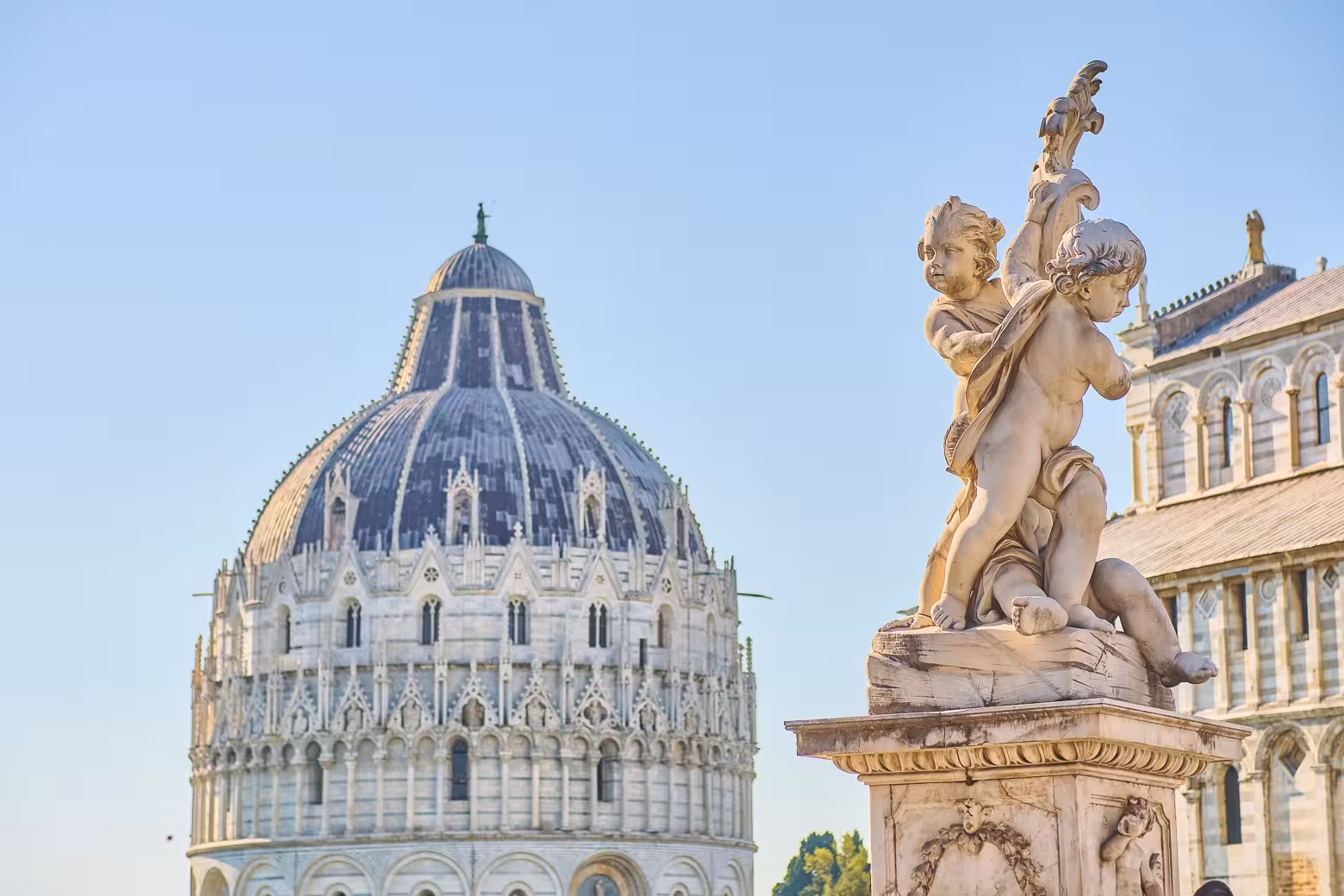 Close-up of Pisa's Baptistery and cherub statue, highlighting the rich architectural details on a Tuscany day tour.