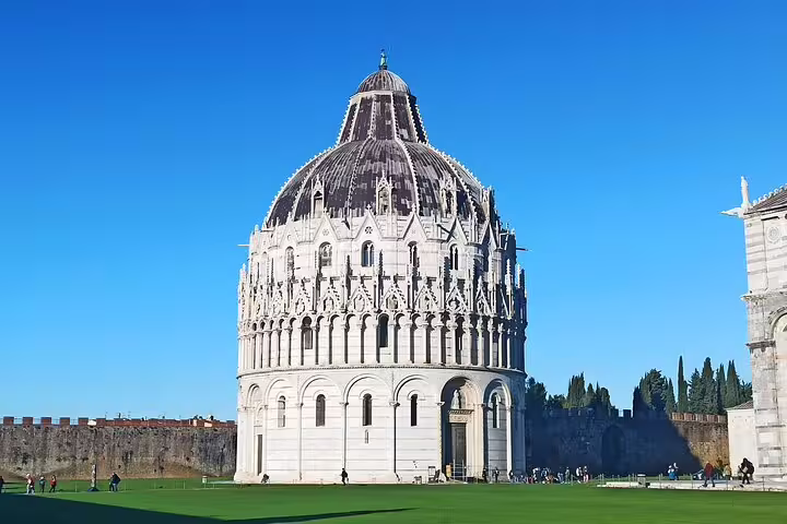 Pisa Baptistery and green lawn under clear blue sky, a highlight of Florence and Pisa day trip from La Spezia and Carrara