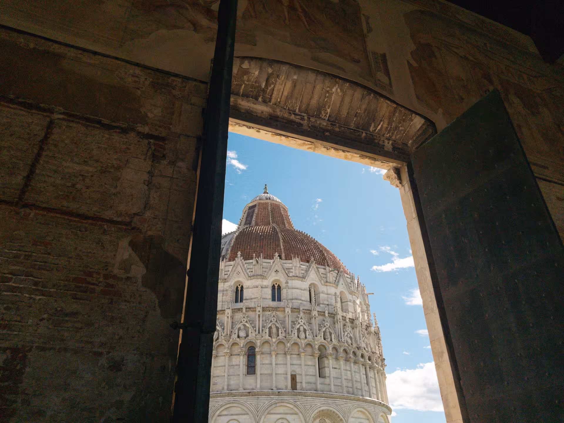 View of Pisa Baptistery from inside a historic building on a full-day private tour from Florence.