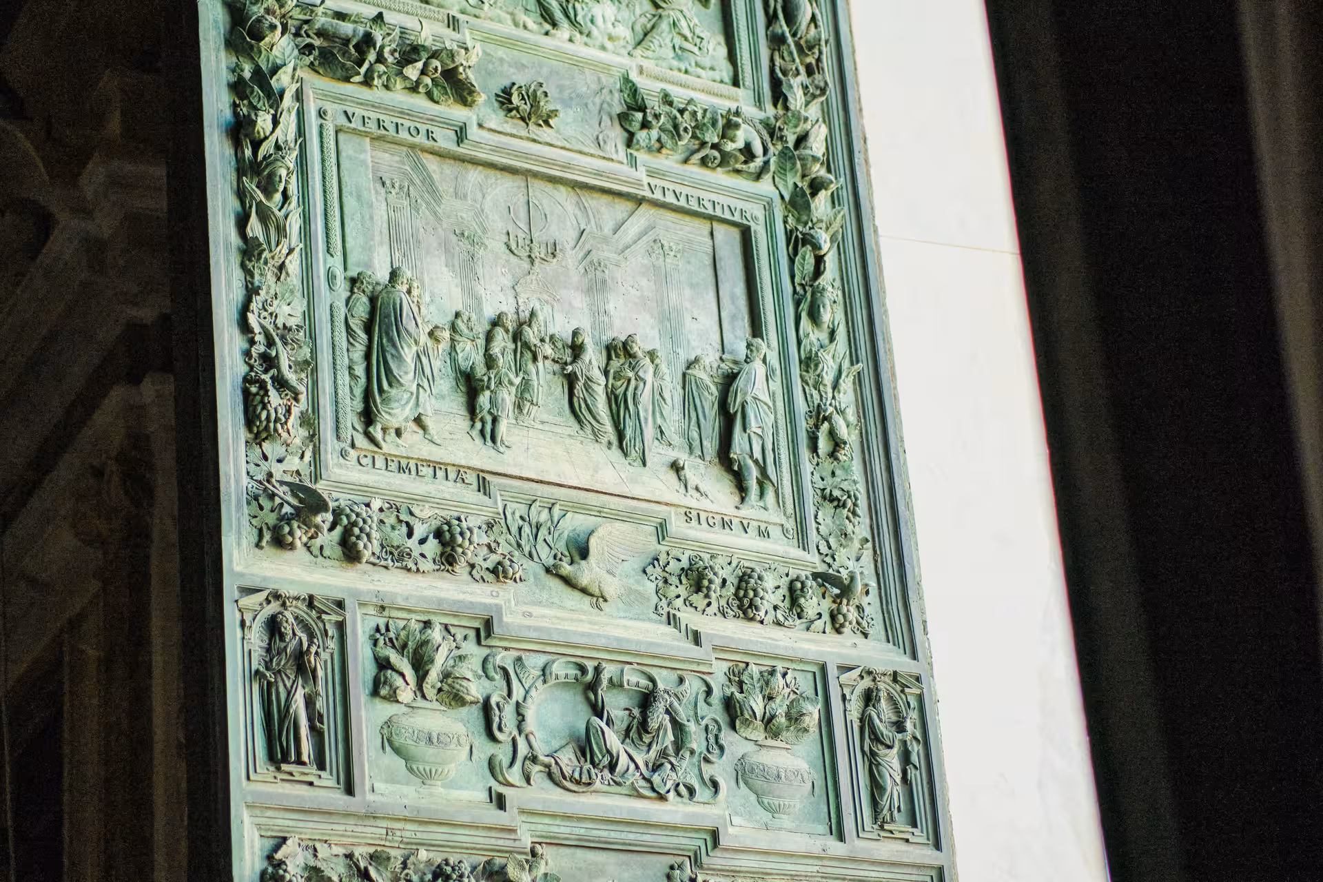 Detailed close-up of ornate bronze reliefs on Pisa Cathedral's doors, showcasing historical artistry.