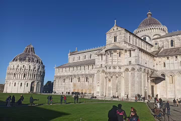 Tourists exploring Pisa Cathedral and Baptistery on a clear day, included in private Pisa and Chianti day trip with wine