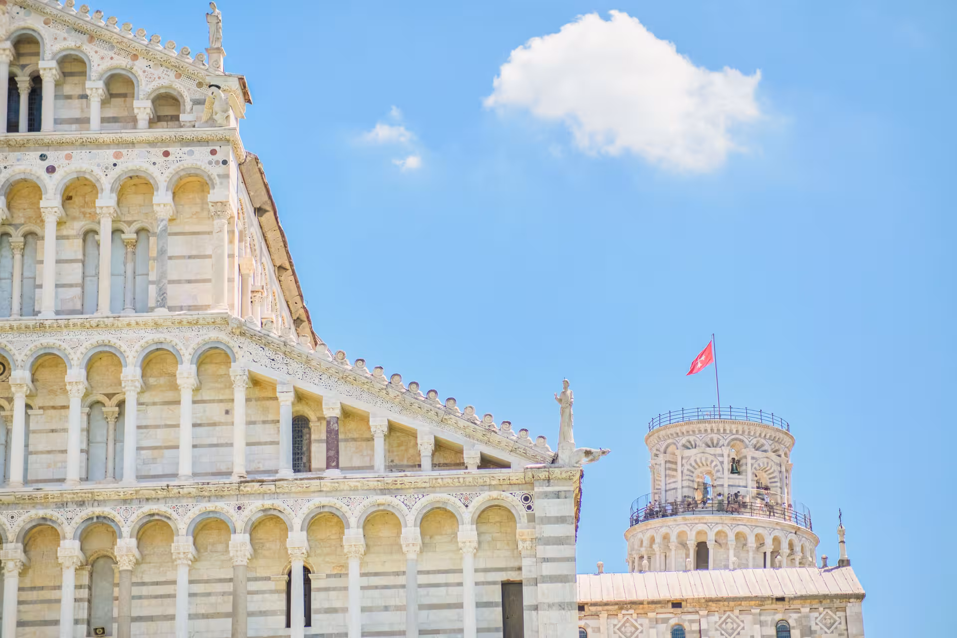 Close-up of Pisa Cathedral facade and Leaning Tower under clear blue skies on a private tour from Florence.