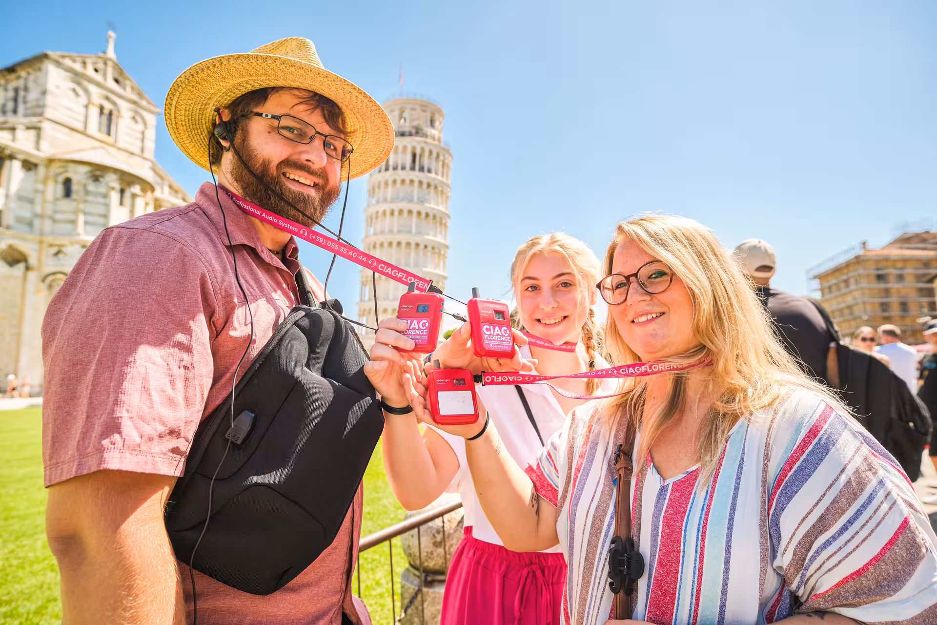 Happy tourists display their audio guides at the Leaning Tower of Pisa during a Livorno shore excursion.