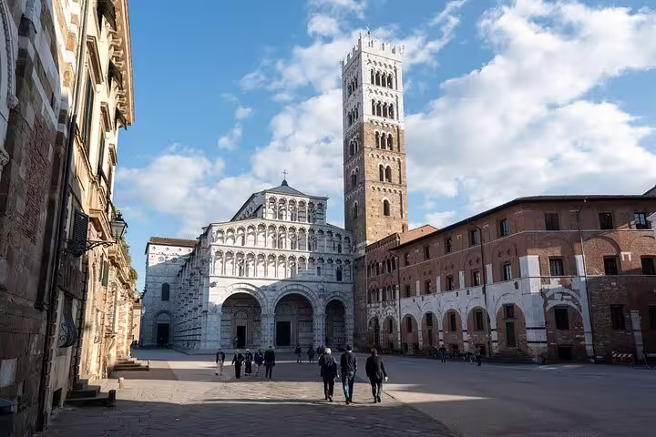 Tourists walking across Piazza San Martino toward Lucca Cathedral and bell tower on Pisa & Lucca private day trip from La Spezia