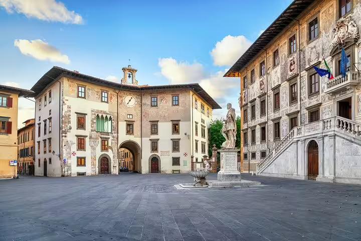 Piazza dei Cavalieri in Pisa with historic Palazzo della Carovana and central statue under blue sky