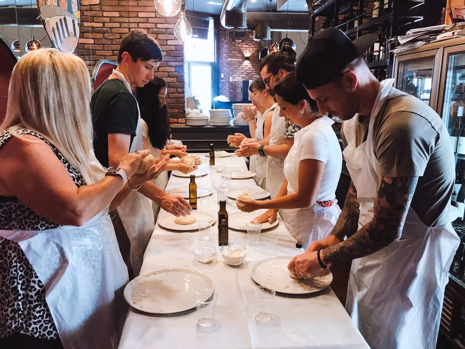 Group of people enjoying a hands-on pizza cooking class at the Jazz Cafe in Rome, dough preparation in progress.