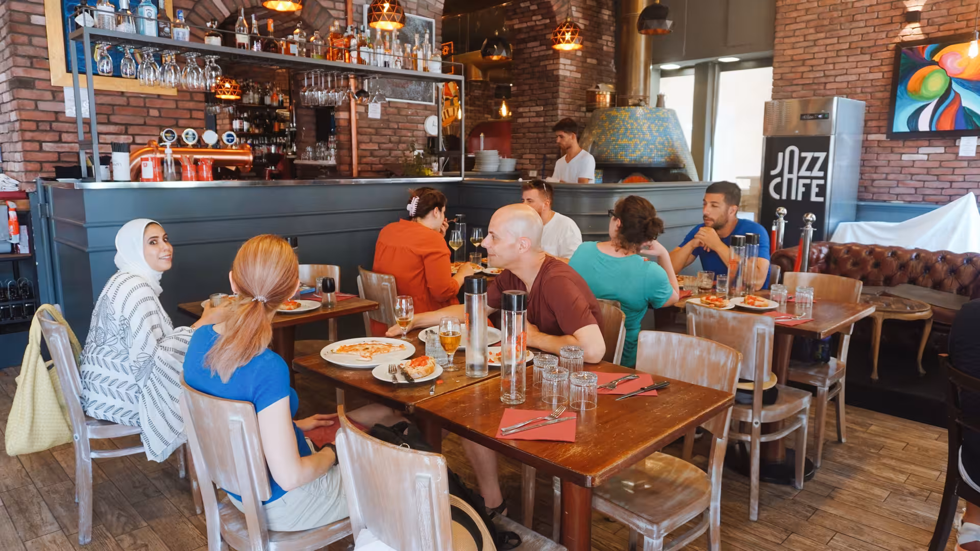 Diners enjoying freshly made pizza inside the cozy and vibrant Jazz Cafe in Rome.